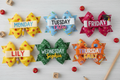 Five custom school-themed hair bows labeled Monday through Friday with personalized child's name
